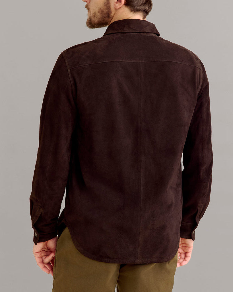 Man wearing a dark brown shirt and navy cap on a gray background