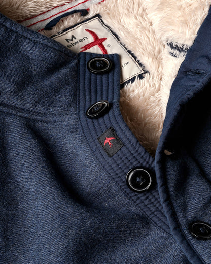 Close-up of a blue coat with buttons and a brand label on a textured background
